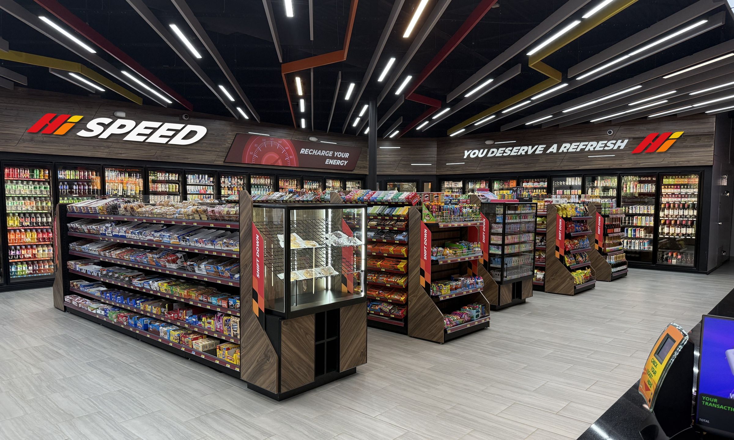 Inside a Hi Speed store: the Hi Speed sign on the wood bulkhead over the cold vault, snack aisles and the black ceiling with red, orange and yellow baffles